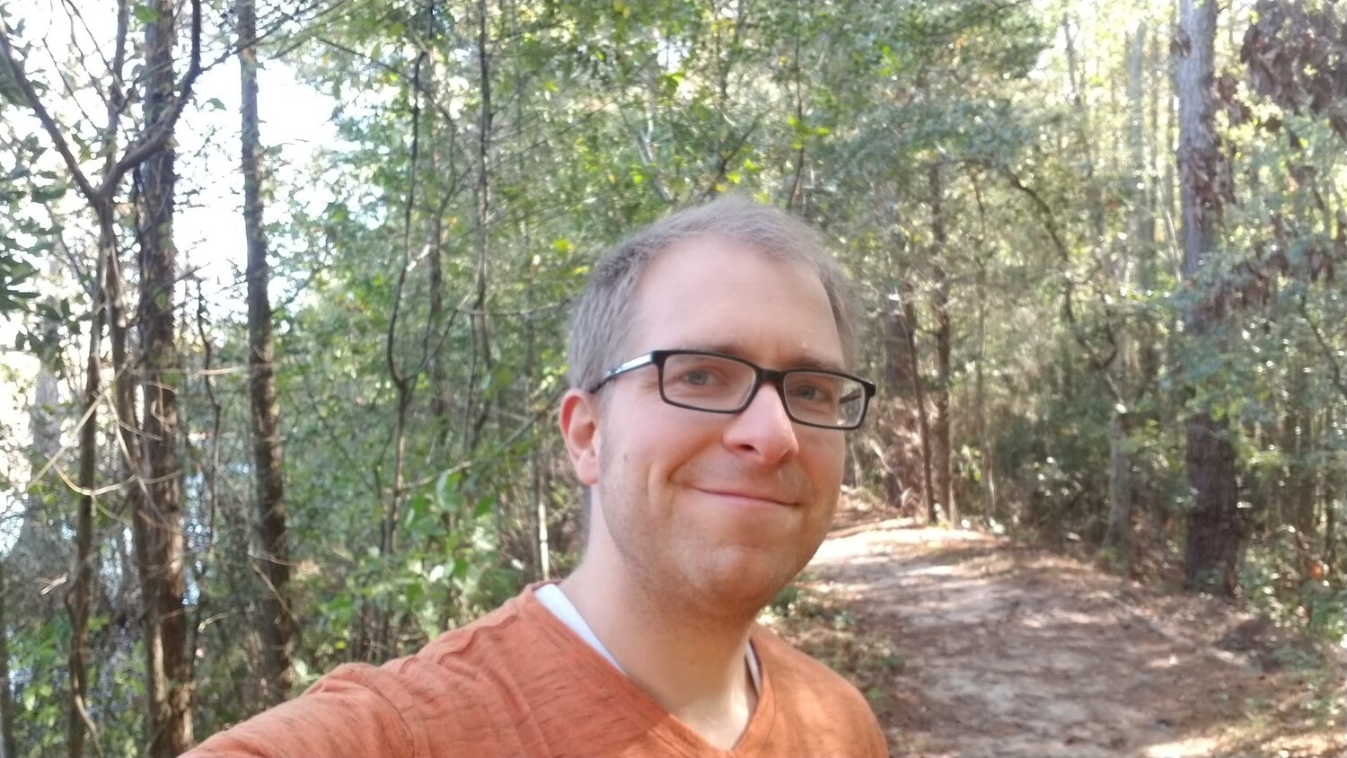Man with glasses and orange shirt smiling on Goodale Lakeside Trail