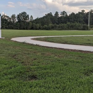 Paved Trail in the middle of cut green grass at Veterans Park Loop Trail